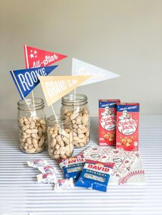 some snacks are sitting in glass jars on a table next to flags and candy bars