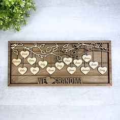 a wooden plaque with hearts hanging from it and the words we love grandma written on it