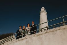 a group of people standing next to each other near a light house