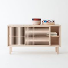 a wooden cabinet with two bowls on top and one bowl sitting on it's side