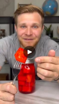 a man holding a fork and jar with jelly in it