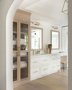 a large bathroom with white cabinets and wood flooring is pictured in this image, there are towels on the shelves