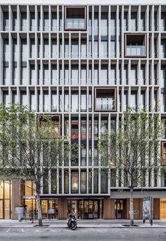 an apartment building with many windows and trees on the side of the street in front of it