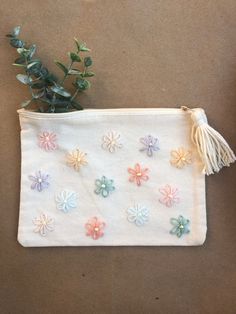 a small white pouch with flowers on it and a plant in the bottom right corner