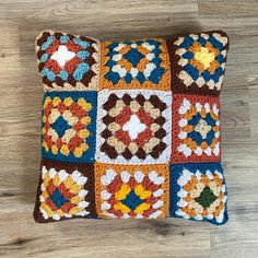 a multicolored crocheted pillow sitting on top of a wooden floor