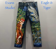 "EAGLE and TIGER When the Heroes Meet" (Eagle is the hero in the air, Tiger is the hero on the ground) hand painted design in wearable art with great details.   All hand painted with permanent good quality latex garment paint used especially for fabric, permanent paint, washable.  This piece of wearable art is striking and guarantee to turn heads... Hand painted by Benjamin Ng. This pair of jeans is : * Brand : LEVI STRAUSS & Co. * US Size : 34 x 32 505 REGULAR STRETCH SITS AT WAIST EXTRA ROOM IN THIGH STRAIGHT LEG Material : 98% Cotton, 2% Elastane. Brand-new with tag. Please check measurements for a good  fit: Length : 43" (109cm) Waist : 34" (86 cm) Inseam : 32" (81 cm) *Washing instruction: Wash separately from any other clothes. Wash inside out, medium or gentle cycle. Do not bleach. Air Tiger, Men Denim Jeans, Meet Guys, Denim Jeans Men, Extra Room, Art Hand, Levi Strauss & Co, Levi Strauss, Paint Designs