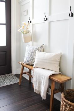 a wooden bench sitting in front of a door with two hooks on it's side