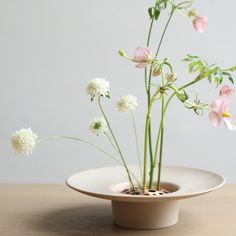 some flowers are in a white bowl on a table