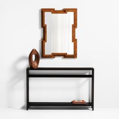 a mirror sitting on top of a wooden shelf next to a vase and an object