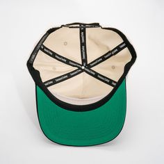 a green and white baseball cap with black stitching on the front, against a white background