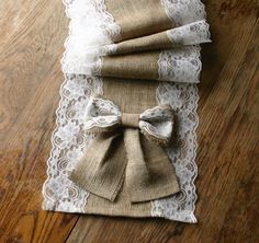 three burlap and white lace napkins with bows on them sitting on a wooden table