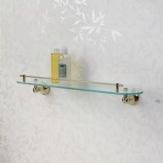 two glass shelves with soap and lotion on them against a wallpapered background