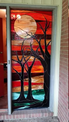 a glass door with trees painted on it in front of a brick wall and red doors