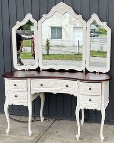 an antique white dressing table with mirror and stool