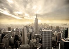 an aerial view of new york city with skyscrapers in the foreground and clouds in the background