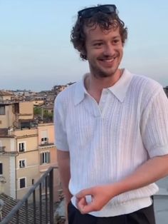 a man standing on top of a balcony next to a building