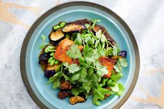 a blue plate filled with vegetables and meat on top of a marble tablecloth covered floor