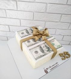 a cake made to look like money with a bow on top and gold decorations around it