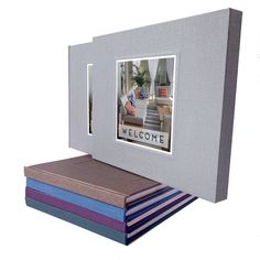 an open photo frame sitting on top of three stacks of folded books in front of a white background