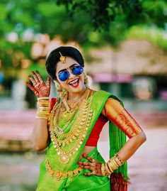 a woman in a green and red sari holding her hand up to the side