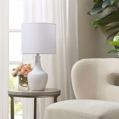 a white lamp sitting on top of a table next to a vase filled with flowers