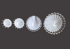 three white parasols sitting next to each other on a black background, with the top one upside down