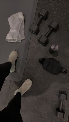 a person standing on the ground with their feet up next to some dumbbells