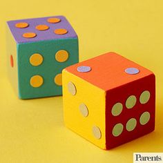 two colorful dices sitting next to each other on a yellow surface with polka dots