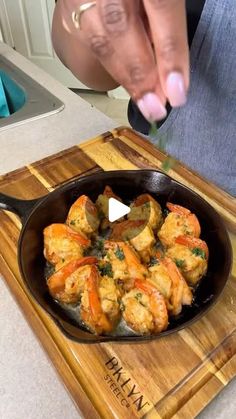 a person cooking food in a skillet on a cutting board