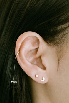 a woman wearing an ear piercing with a star and moon on the side of her ear