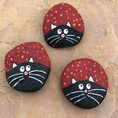 three painted rocks with black cats on them