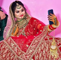 a woman in a red bridal outfit holding a cell phone