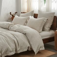 a bed with white linens and pillows in a room next to a lamp on a table