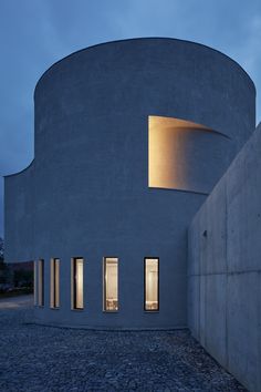 the circular building is lit up at night with light coming from it's windows