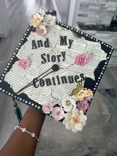 a decorated cap that says and my story continues with flowers on the front, along with words written in cursive writing