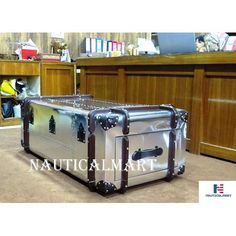 a large metal trunk sitting on the floor in front of a book shelf and desk