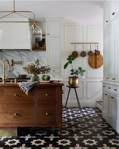 a kitchen with black and white tile flooring next to a wooden cabinet in the center