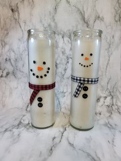 two snowmen made out of glass sitting next to each other on a marble counter