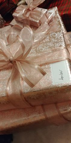 three wrapped presents with ribbons and bows on top of each other, all wrapped in pink paper