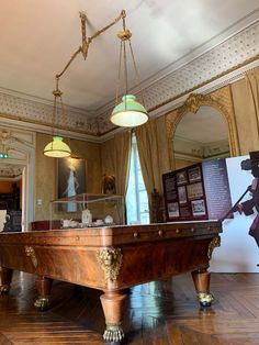 an antique pool table in the middle of a room with two lamps hanging from it's ceiling