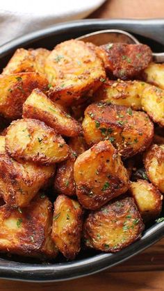 a bowl filled with fried potatoes on top of a wooden table