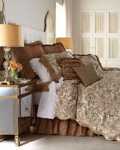 a bed with brown and white comforters in a bedroom next to a mirror on the wall