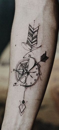 a man's arm with a compass and arrow tattoo on the left inner forearm