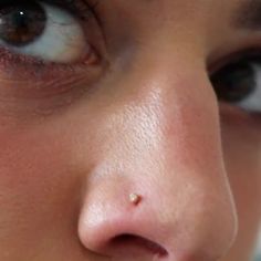 a close up of a woman's nose with piercing on her left cheek and right eye