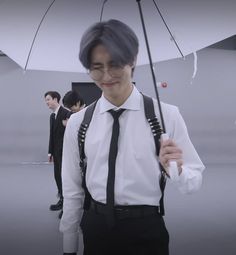 a man in suspenders and tie holding an umbrella