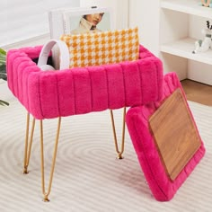 a pink chair and foot stool in a room with white carpeted flooring, bookshelves and pictures on the wall