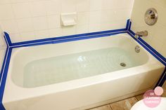 a white bath tub sitting on top of a bathroom floor next to a toilet paper dispenser