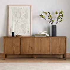 two vases on top of a wooden cabinet next to a plant and a phone