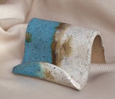 a blue and white ceramic object sitting on top of a bed