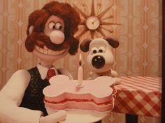 a cartoon character holding a birthday cake with a dog on the table next to it